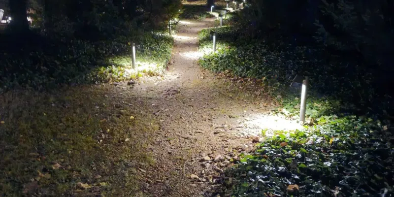 Słupki oświetleniowe wzdłuż ścieżki ogrodowej nocą