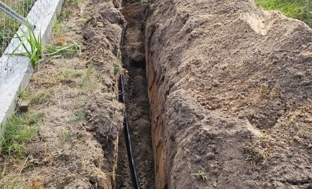 Kabel zasilający ułożony w wykopie wzdłuż ogrodzenia posesji